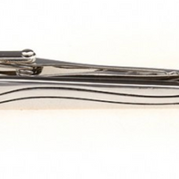 a silver tie clip with an embossed line through it 